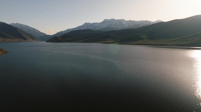 Aerial view of Provo Canyon featuring the calm blue water of the reservoir surrounded by snow-capped mountain peaks under a clear sky in Orem, Utah, United States.