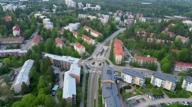 Aerial drone footage of Middle Pohjois-Haaga area in Helsinki, Finland during a spring day. The video shows residential buildings, green spaces, trees, and quiet suburban streets under soft seasonal l