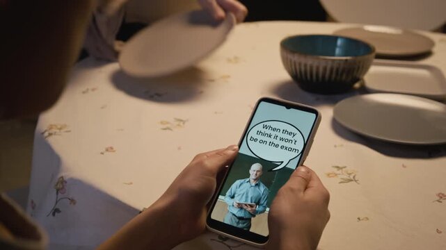 Over shoulder close up shot of unrecognizable teenage boy holding phone and watching short form videos via smartphone while sitting at dinner table, social media obsession in children, copy space
