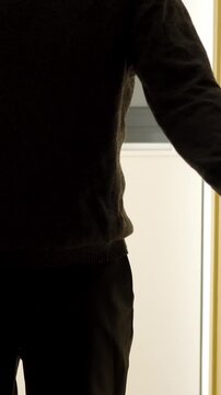 A dark room,a door opens with a silhouette of an unrecognisable man appears, he stands in the doorway and looks at his victim.Focus on shadow.
