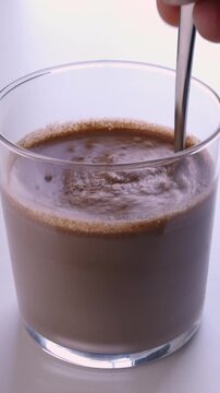 Male hand mixing with scoop of chocolate whey protein powder into a healthy shake for energy for training in a home kitchen. .Boy with nutritional sports supplement for musc.