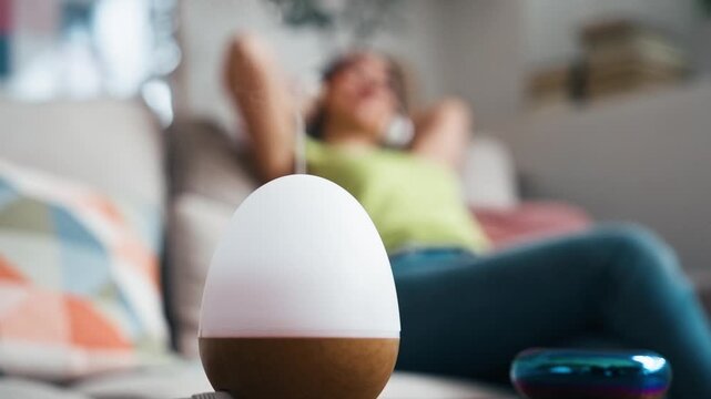 Video of beautiful woman relaxing on a coach while essential oil aroma diffuser humidifier the air at home
