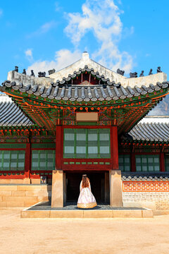 A girl in a traditional Korean costume, hanbok, against the backdrop of ancient Korean architecture.