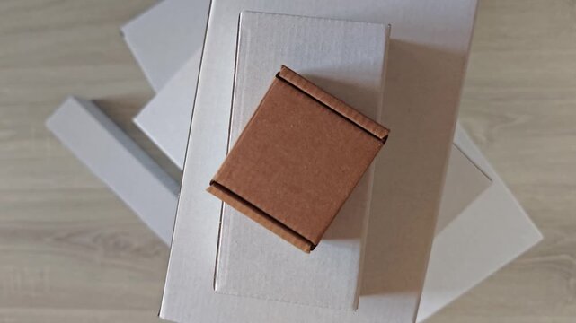 Delivery package arrangement with multiple white boxes stacked and a small brown box placed on top, showcasing a neat organization of shipping materials