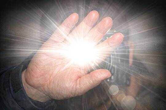 A person's hand holds a bright light in the dark, suitable for crime or thriller scenes
