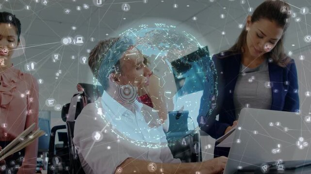 Seated man pointing at laptop causing globe overlaying over team, staff noting for business network