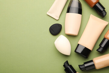 Obraz premium Different liquid foundation and sponges on green background, flat lay. Space for text