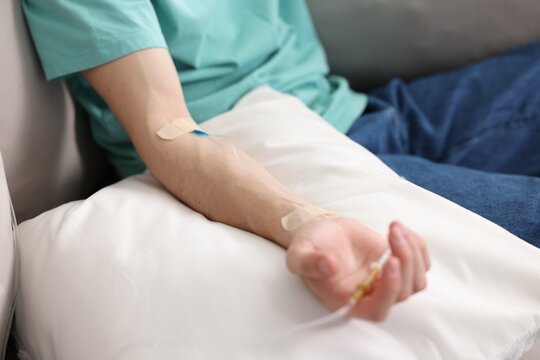 Man with IV drip on sofa at home, closeup