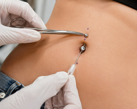 Belly button piercing procedure close up on woman abdomen