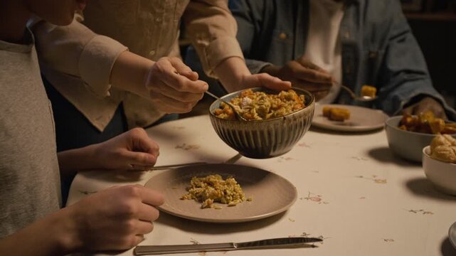 Close up shot of unrecognizable caring mother serving homemade food to family at dinner table enjoying meal together at home, copy space