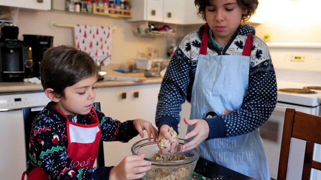 Two children helping in the kitchen to prepare chocolate chip cookies at home