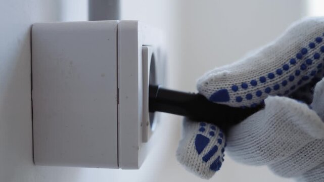 Closeup Of Skilled Electrician Securing Power Cable Into Wall Socket With Safety Emphasis