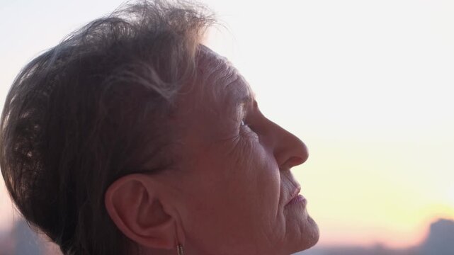 Profile of an elderly woman looking up at the sky at sunset