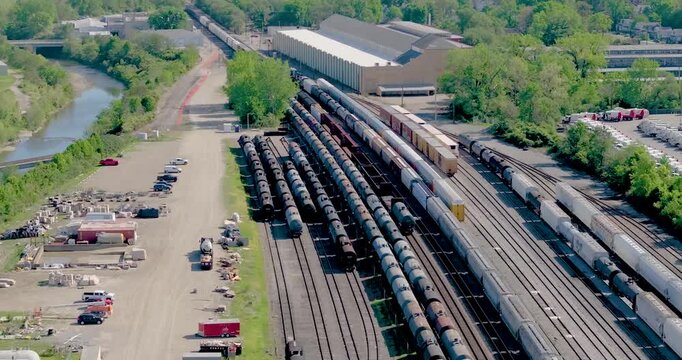 Aerial view of freight train cars on multiple tracks in a rail yard near a large warehouse and a river in Cincinnati, Ohio, United States.