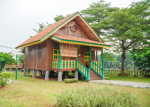 Traditional Betawi stilt house surrounded by tropical landscape representing Jakarta cultural heritage and anniversary celebration theme.