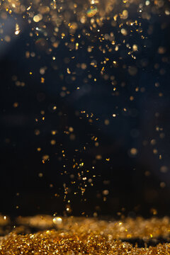 Golden particles falling in a dark setting during a focused moment of light