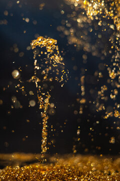 Water droplets create a golden spray in a dark setting during a science experiment