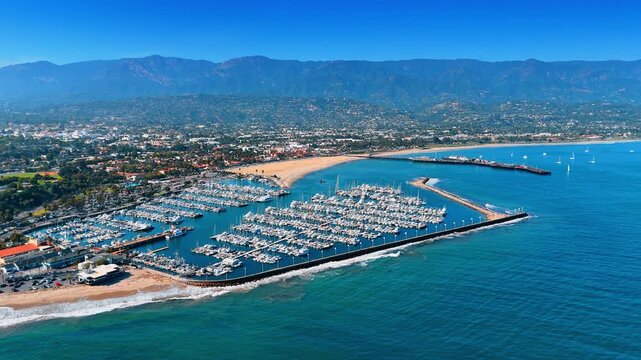 Large yacht club with numerous yachts. Scenic view on gorgeous Santa Barbara, California, USA with hazy mountains in the backdrop. Drone footage.