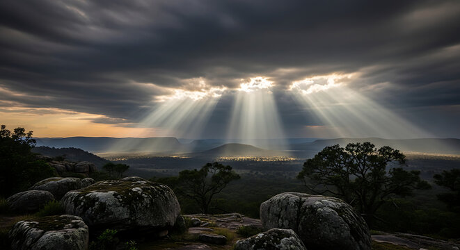 Dramatic Sunlight Breaking Through Clouds Over Rocky Landscape