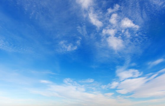 Beautiful blue sky background with light white cirrus clouds on a sunny day.