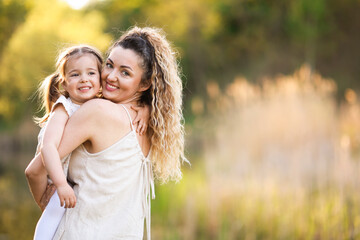 Fototapeta premium Mother with her cute little daughter in nature. Space for text