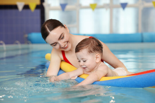 Swimming lesson. Coach teaching little boy to swim with water noodles in pool