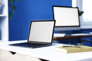 Fototapeta premium Desks with computers, glasses and stationery in office, closeup