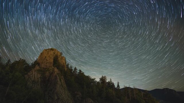 Peak of mountain with spruce forests on the slopes against the backdrop of starry night sky