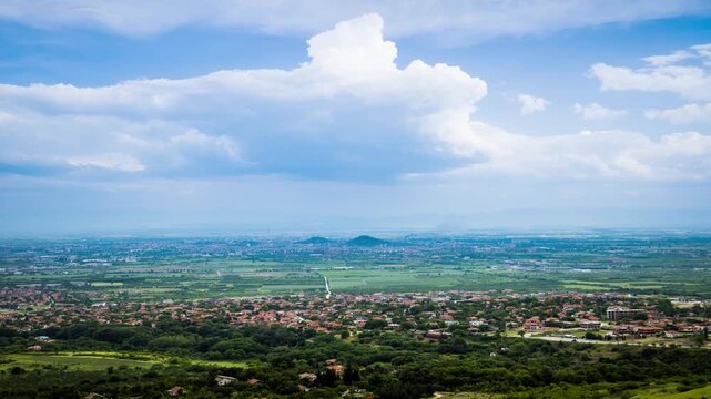 Town Plovdiv with houses and fields against backdrop of Rhodope Mountains and hills covered with forests and cloudy sky