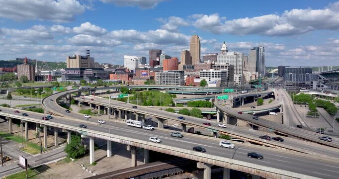 Aerial view of a busy highway interchange with cars driving toward the urban skyline under a blue sky in Cincinnati, Ohio, United States.