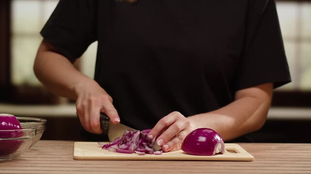 Woman is cutting red onions into slices on a cutting board