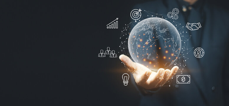 Businessman Holding Glowing Digital Earth Globe with Global Business Network and Finance Icons on Dark Background