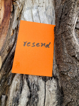 Orange note with the word resend written on it stuck on a wooden trunk