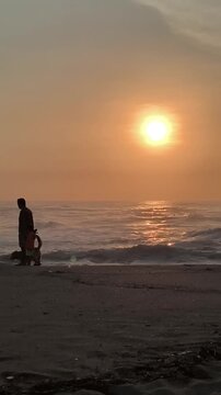 Padre caminando con su hijo y su perro al atardecer frente al mar