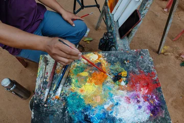 Fotobehang Schilderij SIEM REAP, CAMBODIA, An artist's palette with vibrant oil paints and brushes, ready for creation in an open-air studio environmen at Angkor Wat  © Zenstratus