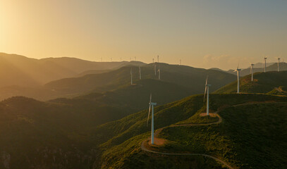 Wind turbines on rolling hills at sunset capture clean, renewable wind energy, forming a serene, expansive landscape that symbolizes sustainable power and a greener future © Nasos Zovoilis