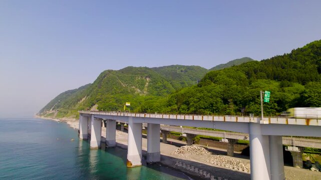 海上から見上げる巨大な橋脚構造 断崖に架かる高速道路のローアングル空撮