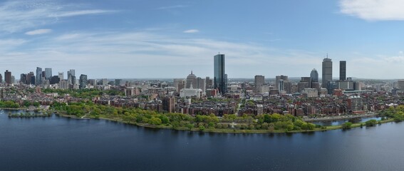 Fototapeta premium Panoramic aerial drone view of Boston Back Bay skyline, Prudential Tower, and Charles River Esplanade on a clear summer day, featuring historic brownstones and city skyscrapers, USA.