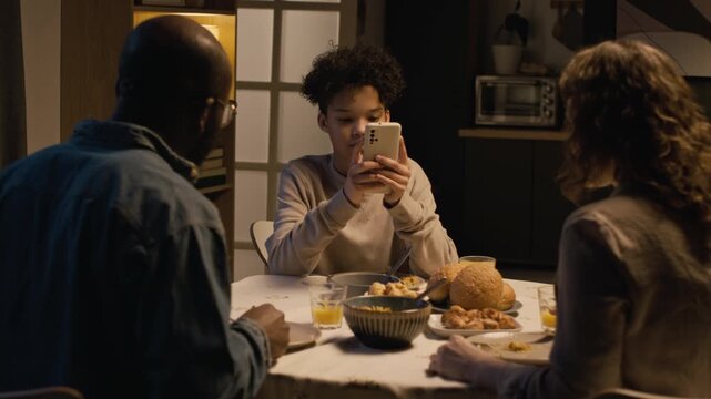 Family conflict scene with strict father scolding son using smartphone at dinner table, teenage boy leaving angrily, gadget addiction in children