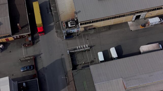 Industrial Loading Zone: An aerial view of a busy industrial loading zone with trucks and vans parked at warehouse docks, showcasing the hustle and bustle of logistics and supply chain operations.