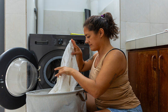 Woman loading laundry into washing machine doing household chores