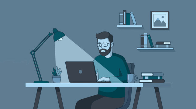 Bearded man with glasses working on his laptop at a minimalist desk under bright lamp light in a dark room, representing professional remote work or focused nighttime study productivity