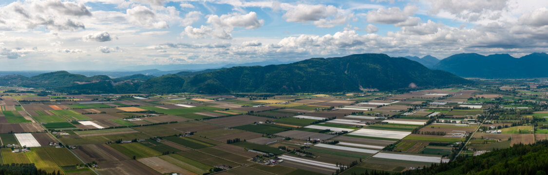 Aerial Panorama of Farmland Valley Near Chilliwack, British Columbia With Mountains and Cloudy Sky