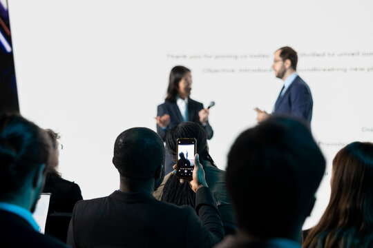 Black attendee recording video of launch event for social media post, creating online content and attending business convention to gain marketing experience. New phone coming soon.