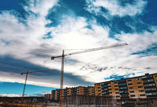 Gr&uacute;a de construcci&oacute;n alta y edificios residenciales bajo un espectacular cielo azul nublado, reportaje editorial sobre desarrollo urbano. Imagen editorial sobre construcci&oacute;n urbana con gr&uacute;a