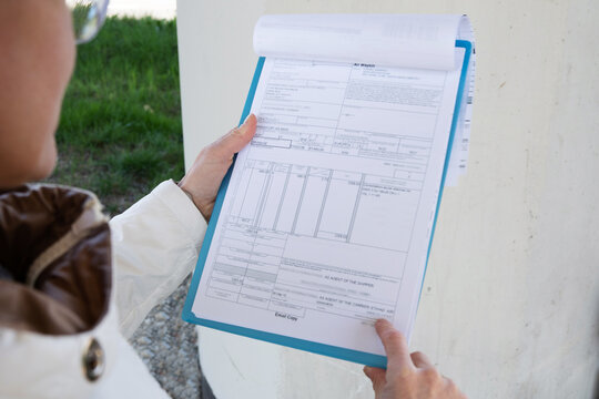 The worker  in  a protective helmet holds a tablet with documents or house air waybill