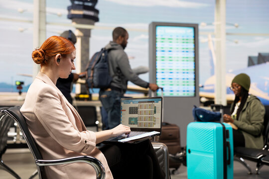 Woman manager analyzing compliance reports on laptop in business lounge, reviewing checklist and business plan. Professional employee preparing for meeting during international travel.