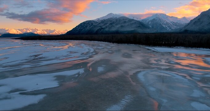Sunset at the Chilkat estuary in Southeast Alaska at low tide with snow and mountains.