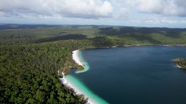 Aerial view of Lake Mckenzie Boorangoora with white silica sand and turquoise water surrounded by dense forest in K'gari, Queensland, Australia.