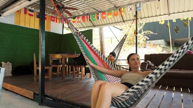 Young woman relaxing and swinging in hammock at hostel